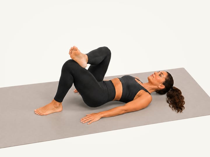 Step 2 of the figure 4 stretch: right ankle crossed over the left thigh, left foot still on the floor