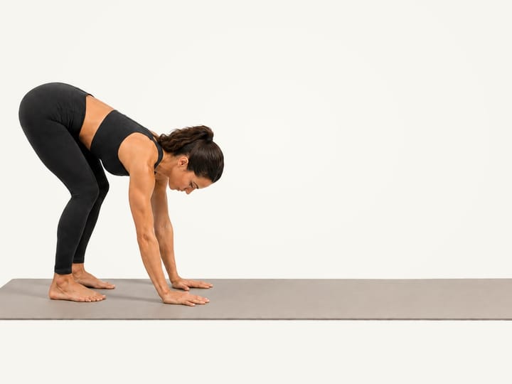 Step 1 of the inchworm: folded forward with soft knees, hands on the floor