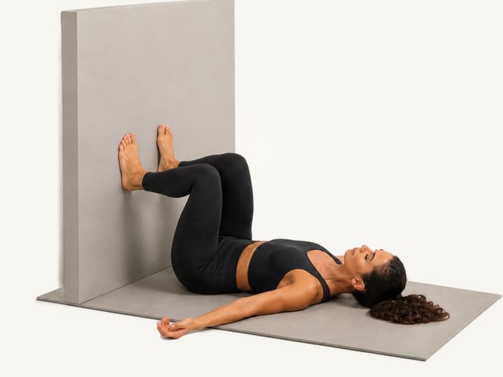 Step 2 of legs up the wall: lying on the back with the knees bent and the feet on the wall