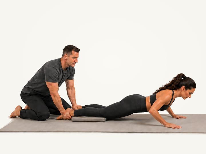 Step 3 of the Nordic curl: caught on both hands near the mat, the partner still holding the ankles