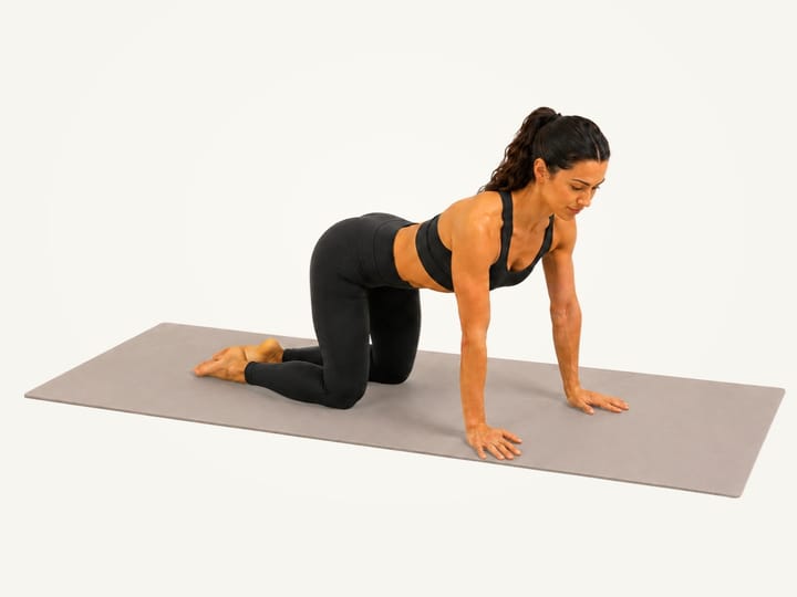 Step 1 of pigeon pose: on all fours, hands under the shoulders and knees under the hips