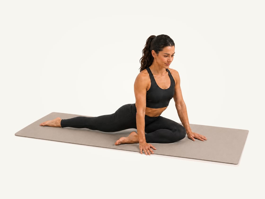 Pigeon pose: right shin diagonal across the mat, left leg straight behind, torso upright on both hands