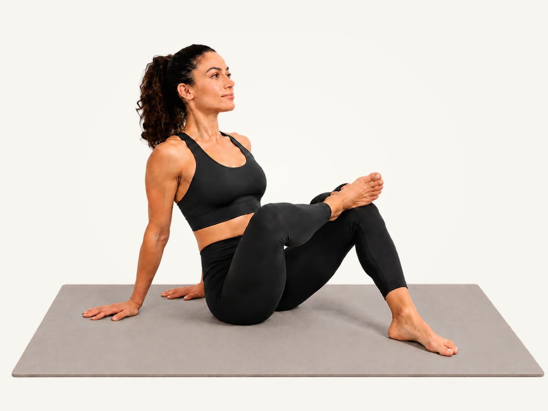 Seated figure 4 stretch: sitting on the mat with the hands behind and the right ankle crossed over the left thigh