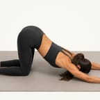 Puppy pose: hips over the knees, arms reaching forward, chest lowered towards the mat